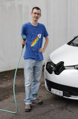Clark Winkelmann devant sa voiture avec un câble de recharge de véhicule électrique